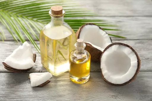 Rozpoltený kokos a vedľa neho fľaštičky a kokosovým olejom